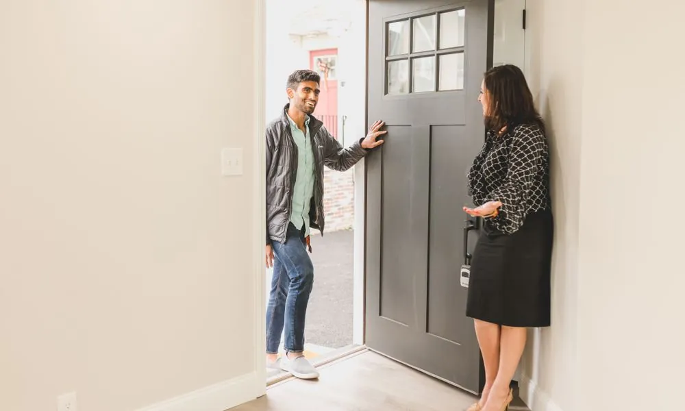 Asesora inmobiliaria recibe en la puerta a un interesado que visita una casa, momento clave con prospectos inmobiliarios